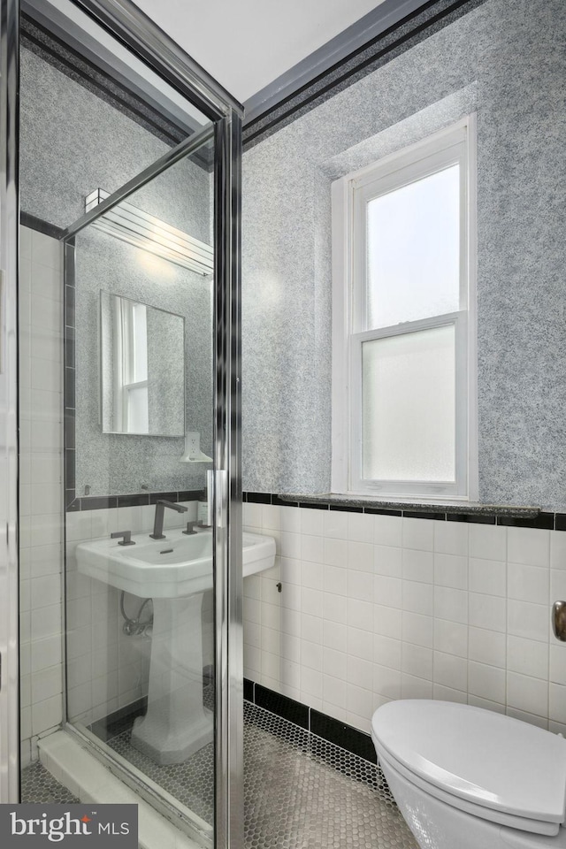 bathroom featuring tile patterned floors, toilet, plenty of natural light, and tile walls