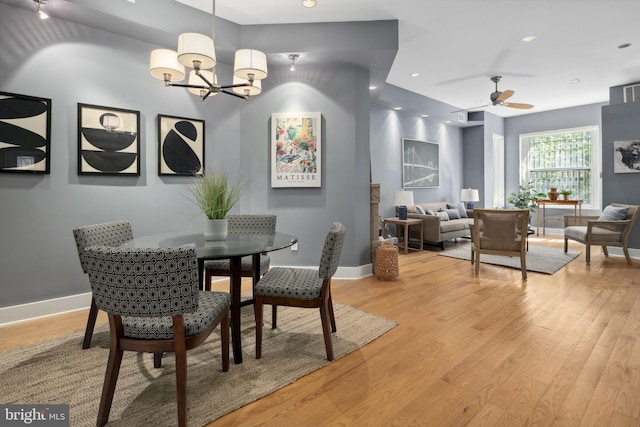 dining area featuring light hardwood / wood-style flooring and ceiling fan with notable chandelier