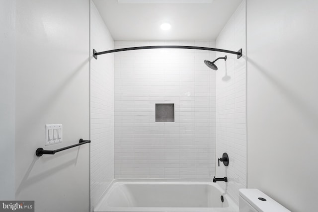 bathroom featuring tiled shower / bath combo and toilet