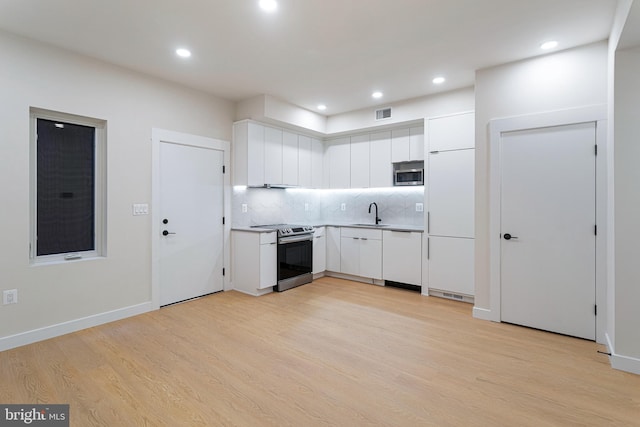 kitchen featuring white cabinetry, light hardwood / wood-style flooring, and appliances with stainless steel finishes