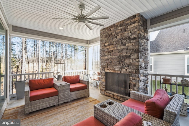 sunroom / solarium with ceiling fan, a healthy amount of sunlight, an outdoor stone fireplace, and wooden ceiling