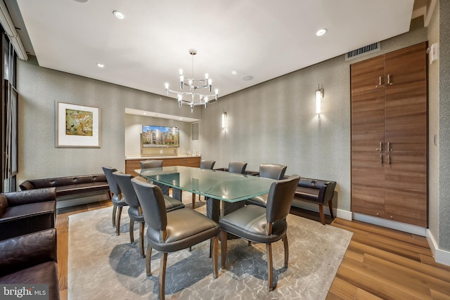 dining room with light wood-type flooring and an inviting chandelier