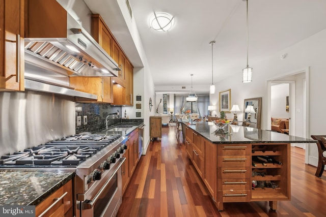 kitchen featuring wall chimney exhaust hood, pendant lighting, stainless steel appliances, tasteful backsplash, and a kitchen island