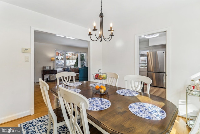 dining area with light wood-type flooring and an inviting chandelier