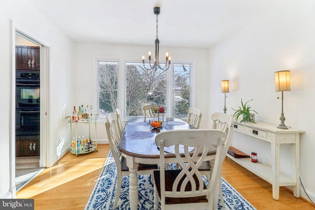 dining space featuring light hardwood / wood-style floors and an inviting chandelier