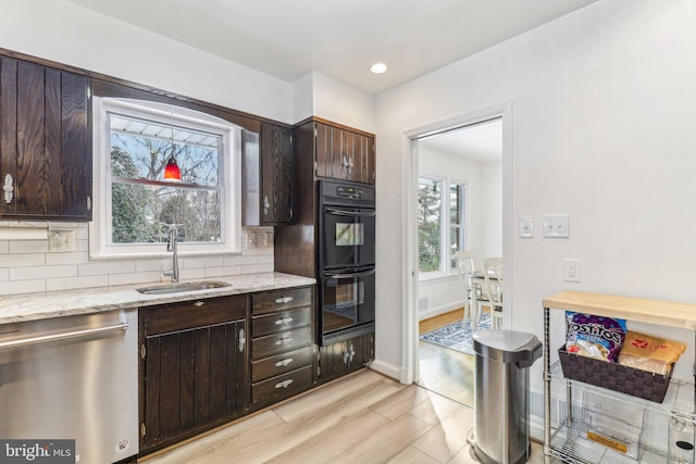 kitchen featuring dishwasher, dark brown cabinetry, double oven, and sink