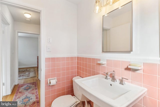 bathroom featuring wood-type flooring, toilet, tile walls, and sink