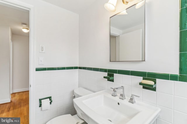 bathroom with hardwood / wood-style flooring, toilet, sink, and tile walls