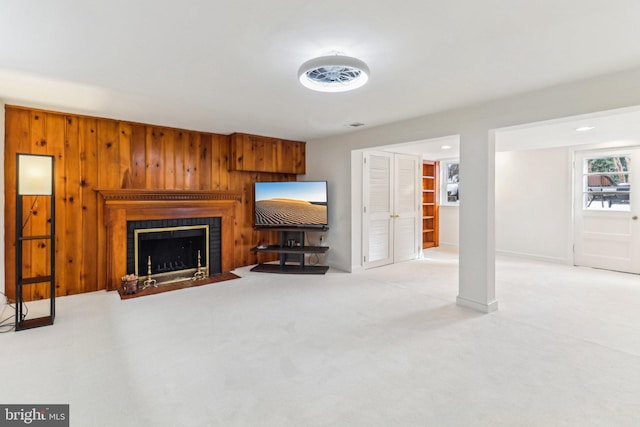 living room featuring wood walls, a fireplace, and light carpet