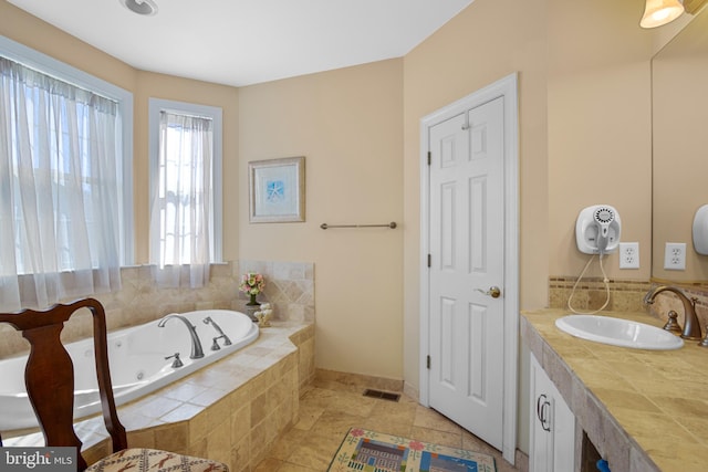 bathroom featuring tiled bath, tile patterned flooring, and vanity