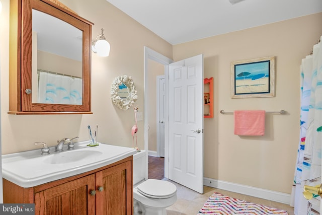 bathroom with toilet, vanity, and tile patterned floors