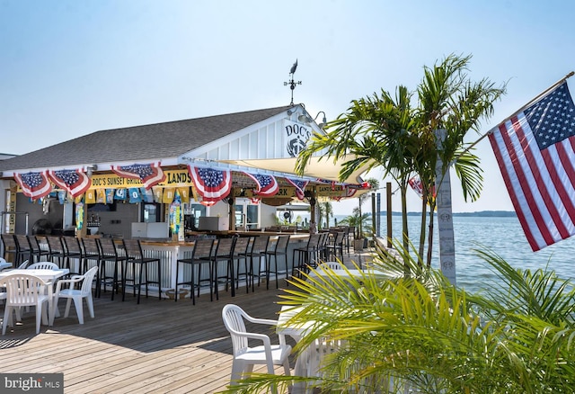 wooden terrace featuring a water view and an outdoor bar