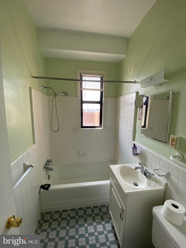 full bathroom with toilet, vanity, tile walls, and tiled shower / bath