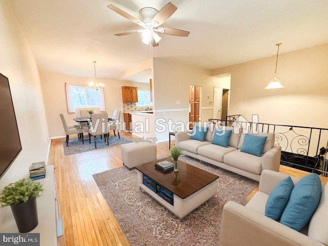 living room with hardwood / wood-style floors and ceiling fan with notable chandelier