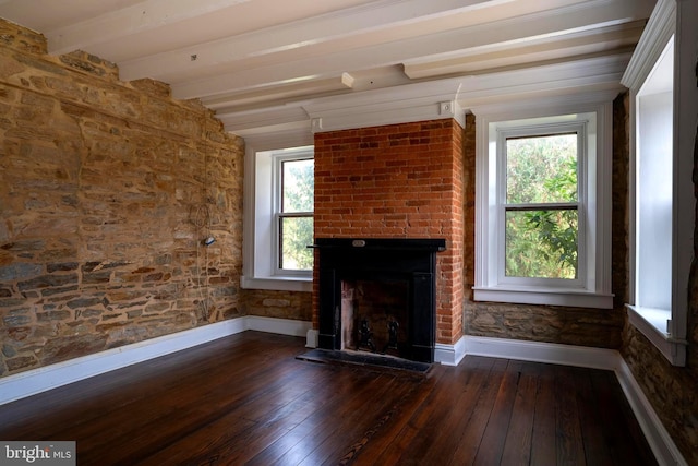 unfurnished living room featuring beam ceiling, a wealth of natural light, and dark wood-type flooring