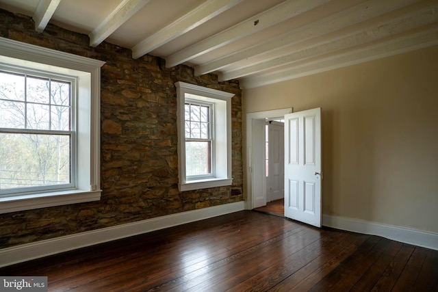 spare room with dark hardwood / wood-style floors and beam ceiling