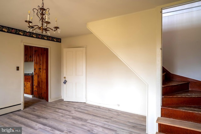 stairway with hardwood / wood-style flooring, a baseboard heating unit, and a notable chandelier