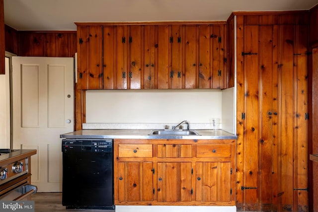 kitchen with stainless steel counters, sink, black dishwasher, hardwood / wood-style flooring, and range