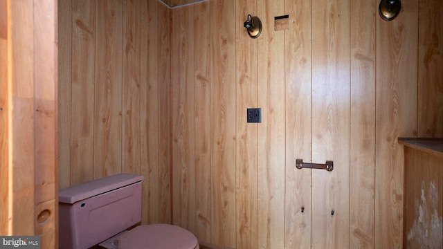 bathroom with toilet and wooden walls