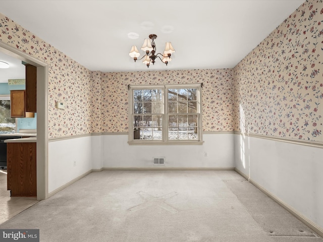 carpeted empty room featuring a notable chandelier