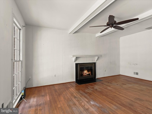 unfurnished living room with beam ceiling, dark wood-type flooring, and ceiling fan