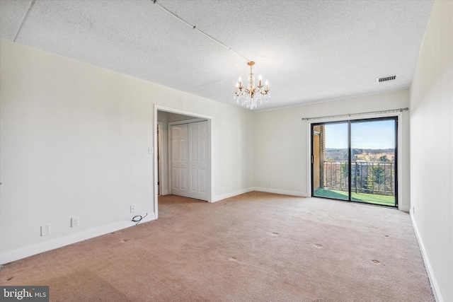 unfurnished room with a textured ceiling, light carpet, and an inviting chandelier