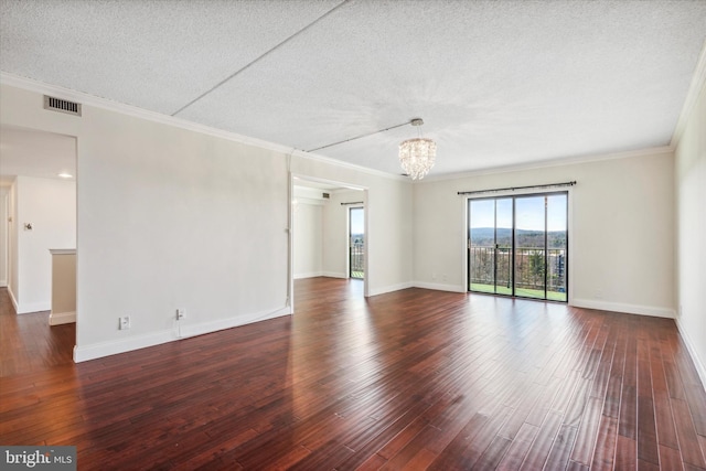 spare room featuring dark wood-type flooring, an inviting chandelier, crown molding, and a textured ceiling