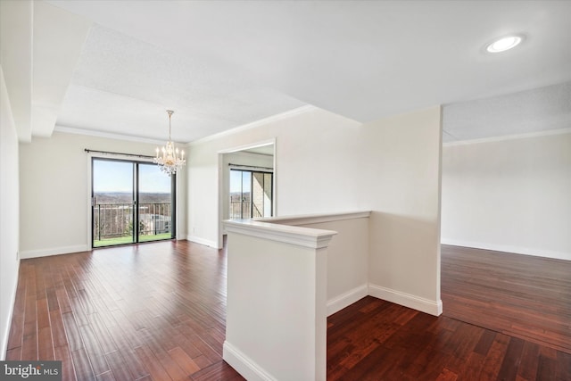 unfurnished room featuring dark wood-type flooring, crown molding, and a chandelier