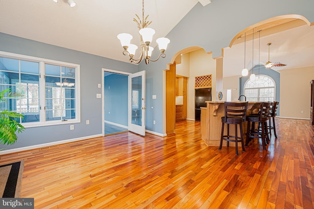 kitchen with pendant lighting, ceiling fan with notable chandelier, hardwood / wood-style flooring, and lofted ceiling