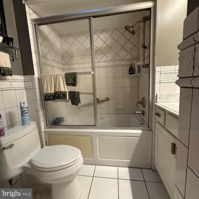 bathroom featuring combined bath / shower with glass door, tile walls, toilet, and tile patterned floors