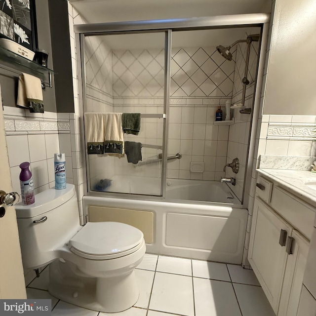 full bath featuring bath / shower combo with glass door, tile walls, toilet, and tile patterned floors