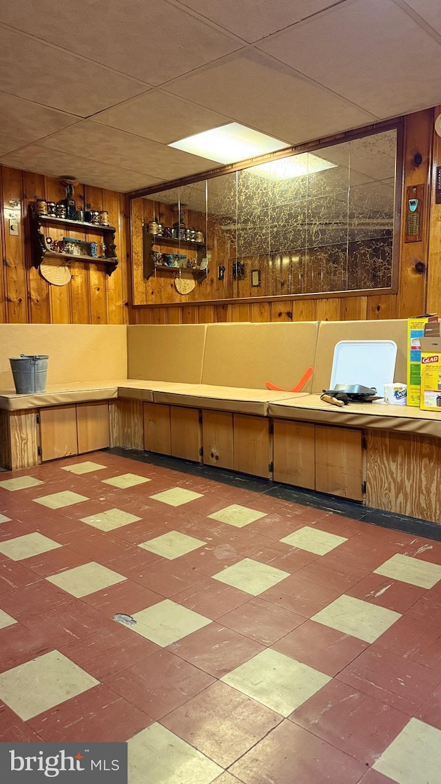 basement featuring tile patterned floors and wooden walls