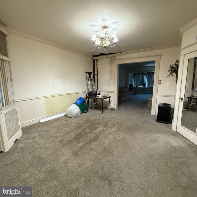 interior space with a chandelier, carpet floors, and ornamental molding