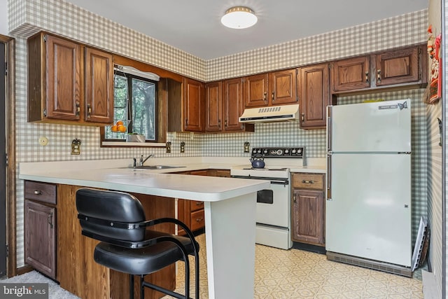 kitchen with a breakfast bar area, kitchen peninsula, sink, and white appliances