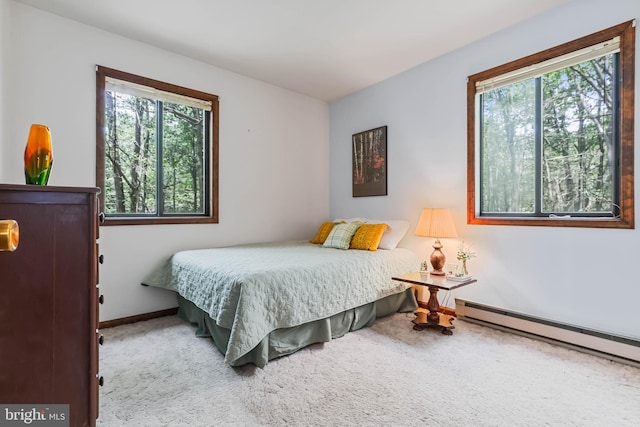 bedroom with light carpet and a baseboard heating unit