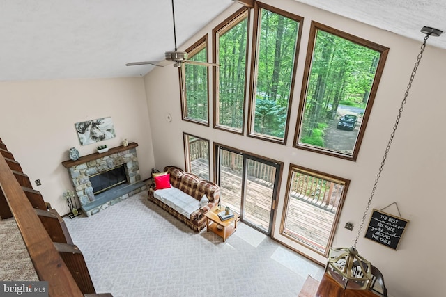 living room featuring ceiling fan, a healthy amount of sunlight, a stone fireplace, and high vaulted ceiling