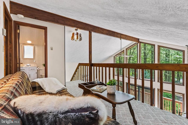 living area with vaulted ceiling with beams and a textured ceiling