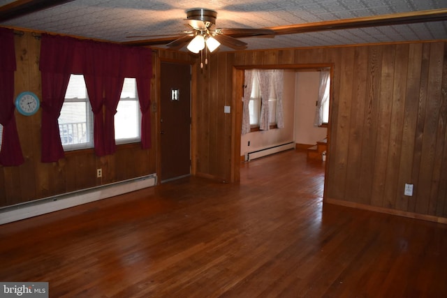 interior space with a baseboard heating unit, ceiling fan, wood walls, and wood finished floors