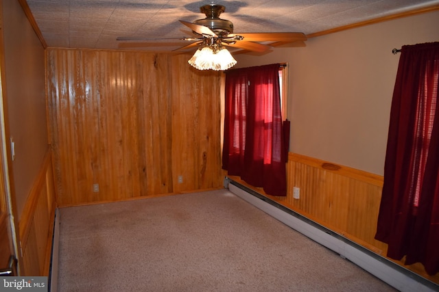 spare room featuring a wainscoted wall, a baseboard radiator, wooden walls, and ceiling fan