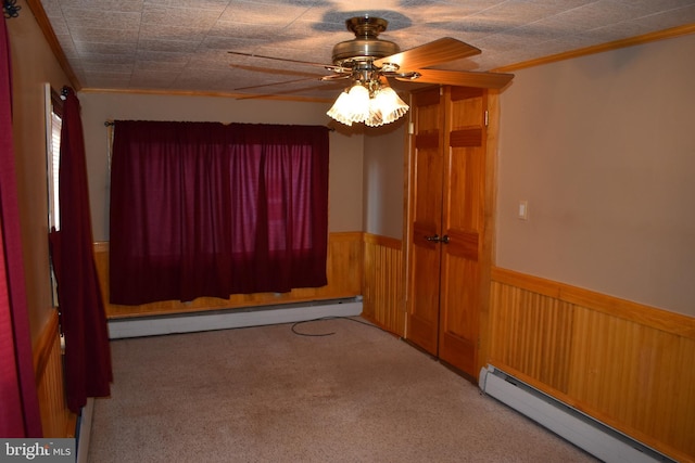 empty room featuring a baseboard radiator, a baseboard heating unit, light carpet, wainscoting, and crown molding