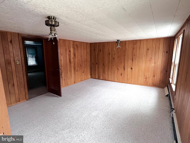 unfurnished dining area with carpet, wooden walls, and a baseboard radiator