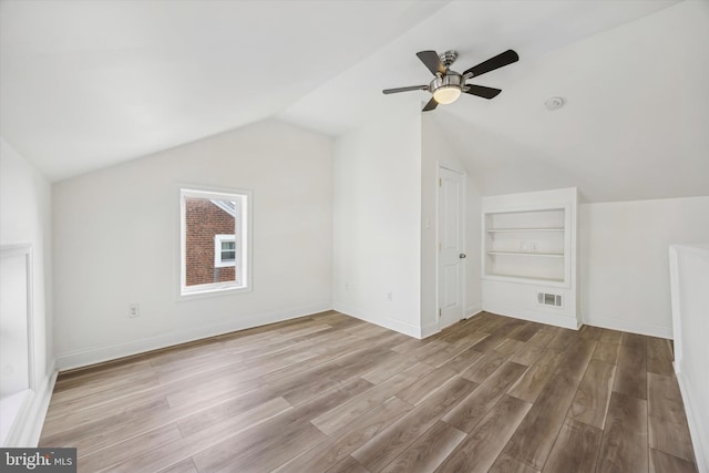 additional living space featuring ceiling fan, light hardwood / wood-style floors, built in features, and vaulted ceiling