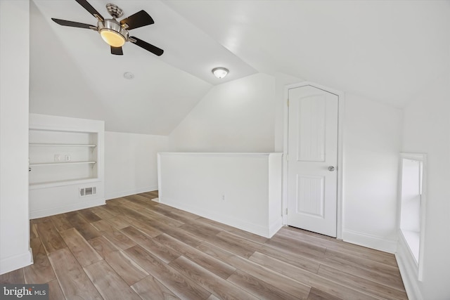 additional living space featuring vaulted ceiling, light hardwood / wood-style floors, built in features, and ceiling fan