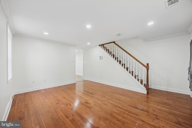 unfurnished living room featuring hardwood / wood-style floors and crown molding