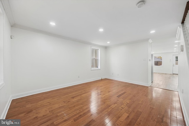 spare room with a healthy amount of sunlight, crown molding, and wood-type flooring