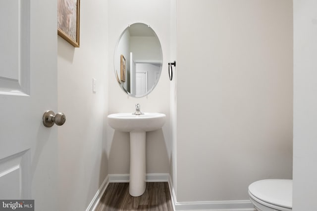 bathroom with wood-type flooring, toilet, and sink