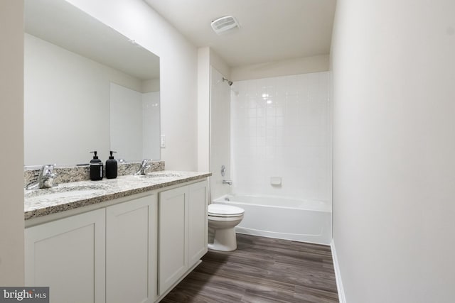 full bathroom featuring hardwood / wood-style floors, vanity, tiled shower / bath combo, and toilet