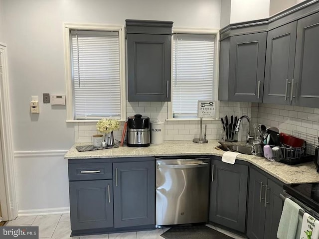 kitchen featuring sink, light stone counters, stainless steel dishwasher, backsplash, and light tile patterned flooring