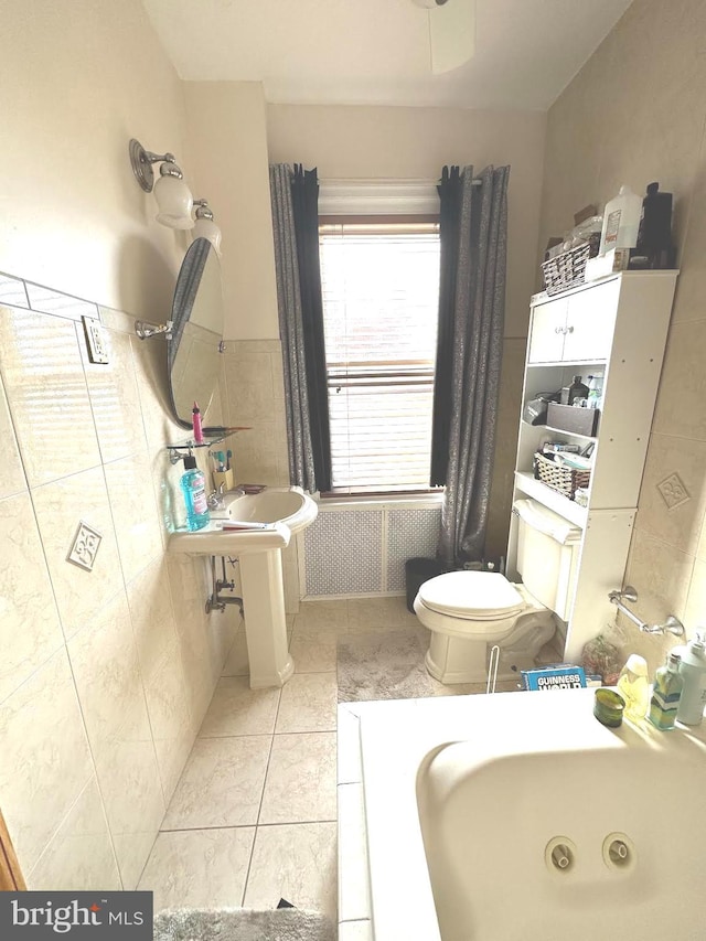 bathroom with tile patterned floors, sink, toilet, and tile walls