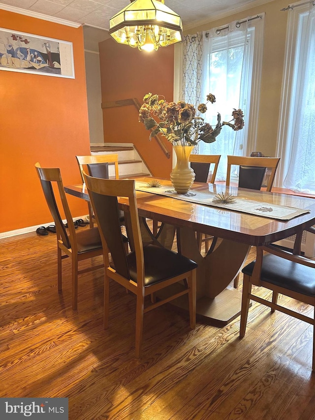 dining area with wood-type flooring, crown molding, and an inviting chandelier